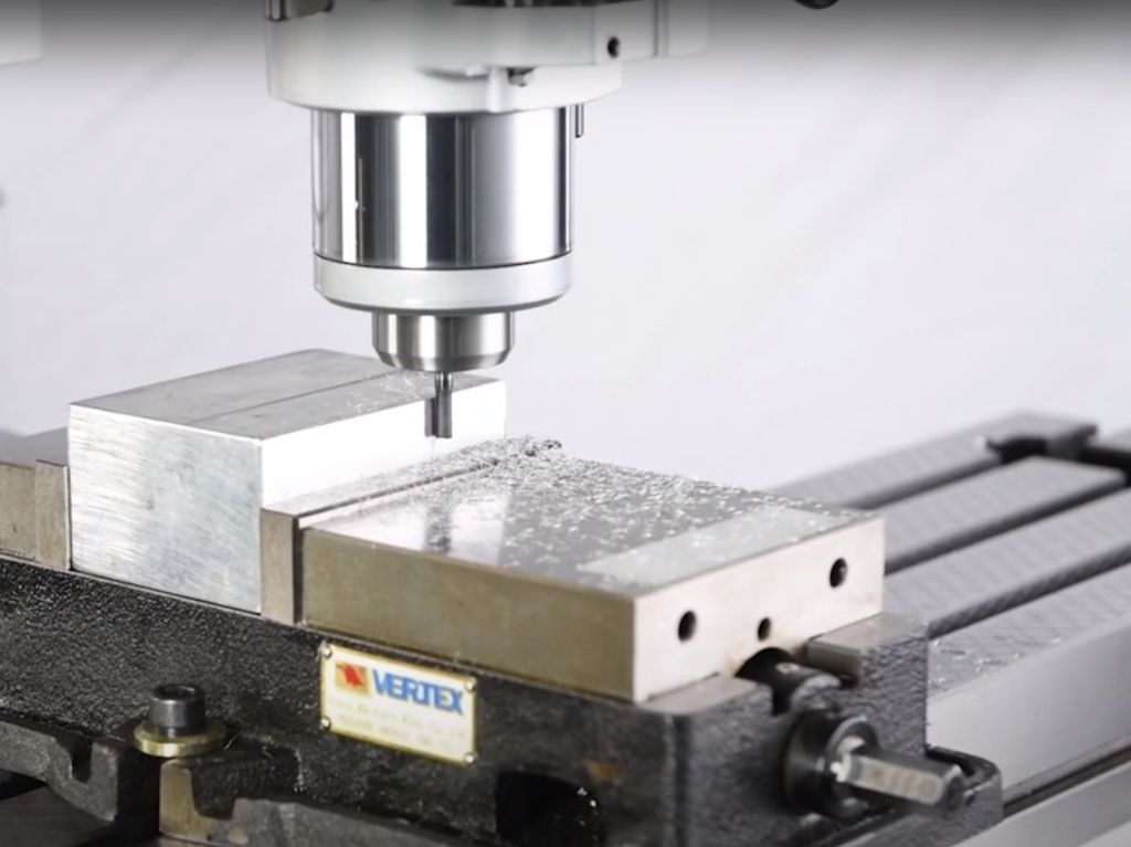 Manual Machines Manual milling machine cutting aluminum block held in a vise, showcasing hands-on machining precision for prototyping, repair, and small-batch work.